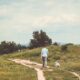 Longshot of a man and his dog walking down a dirt path.